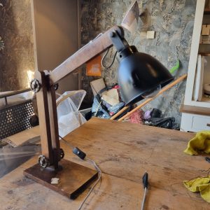 zwart metaal met hout, Hoogendam Interiors By Mooss,  lampen kap met hout onderstel, tafel/bureaulamp/lamp , De afmeting van het onderstuk is:  15,5 x 23 cm.  De balkjes van de lamp zijn 35 cm lang.  De doorsnede van de lampenkap is: 14 cm. (op voorraad) V1