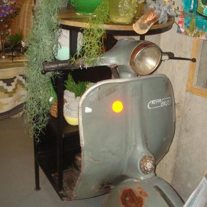 Grijze scooter ronde houten bar tafel en zwart metalen onderstel en opberg rek achterkant, Varios plant tafelVarios, met onder het tafelblad kastje met 1 midden plank, 112 cm hoog, 105 cm breed, 48 cm lengte en tafelblad 60cm doorsnede, (op voorraad) V1